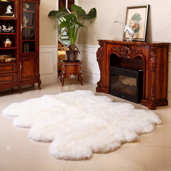 Ivory sheepskin rug in front of a carved fireplace